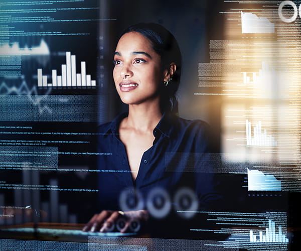 Futuristic images of graphs and data superimposed over a photograph of a young woman working at a computer.