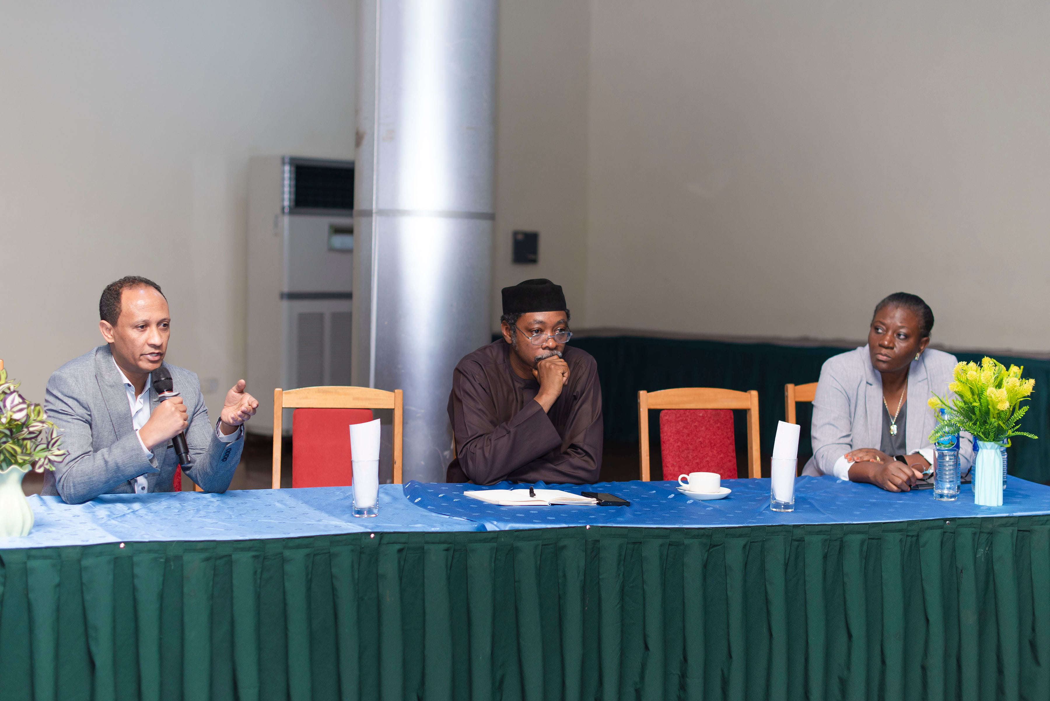 Merih Tesfazghi, Professor Idris, and Olajumoke Oladipo, sitting at a panel table. 
