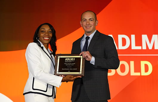 A woman holding up an award while a group of other people look on and smile.