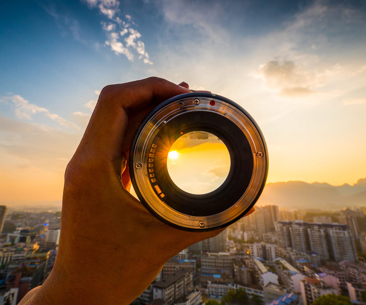 Hand holding cylindrical object with sun showing through other end