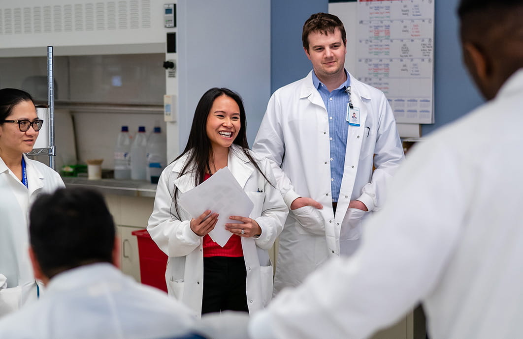Laboratorians meeting in a lab and smiling at each other.