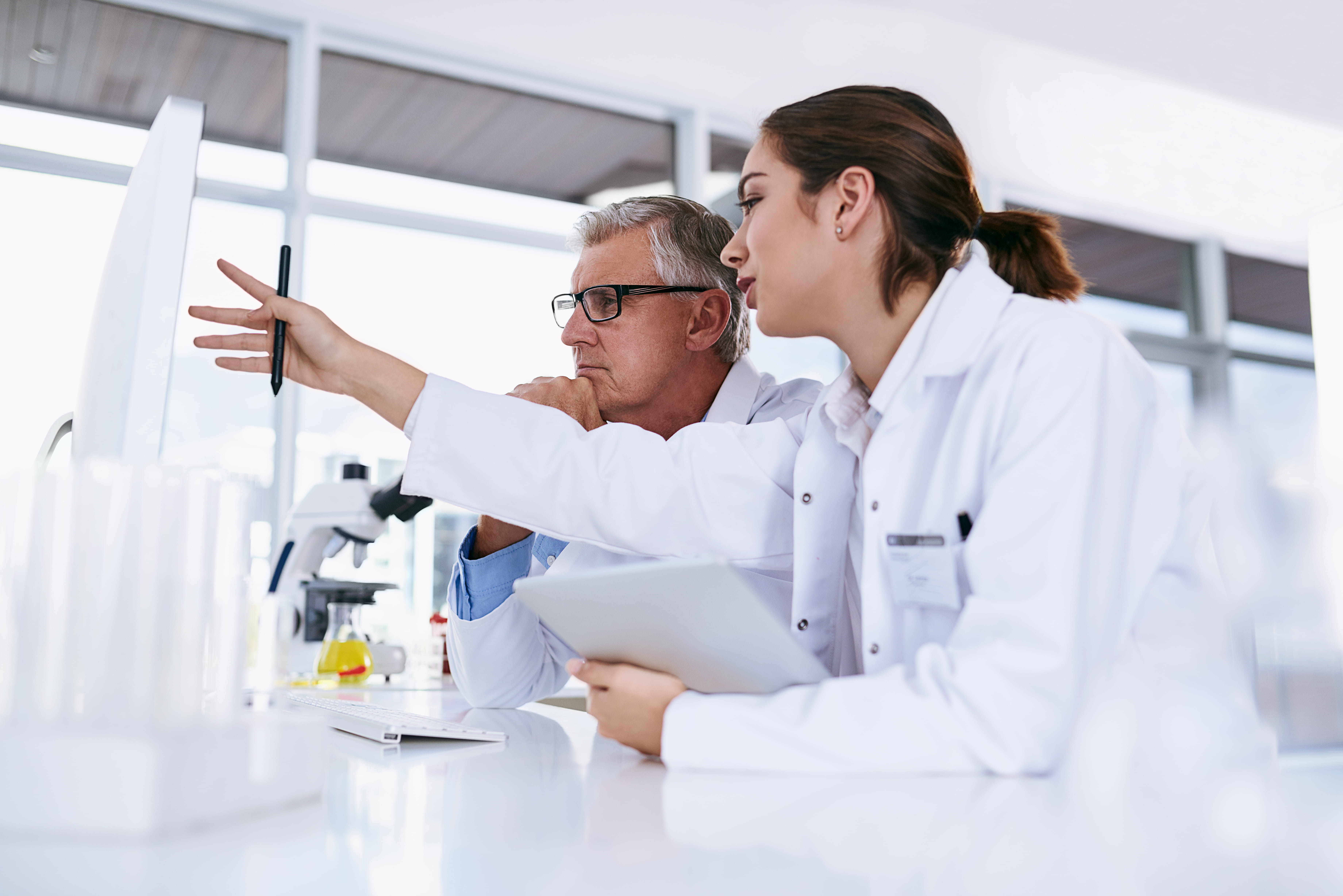 A male and female lab worker pointing to computer monitor