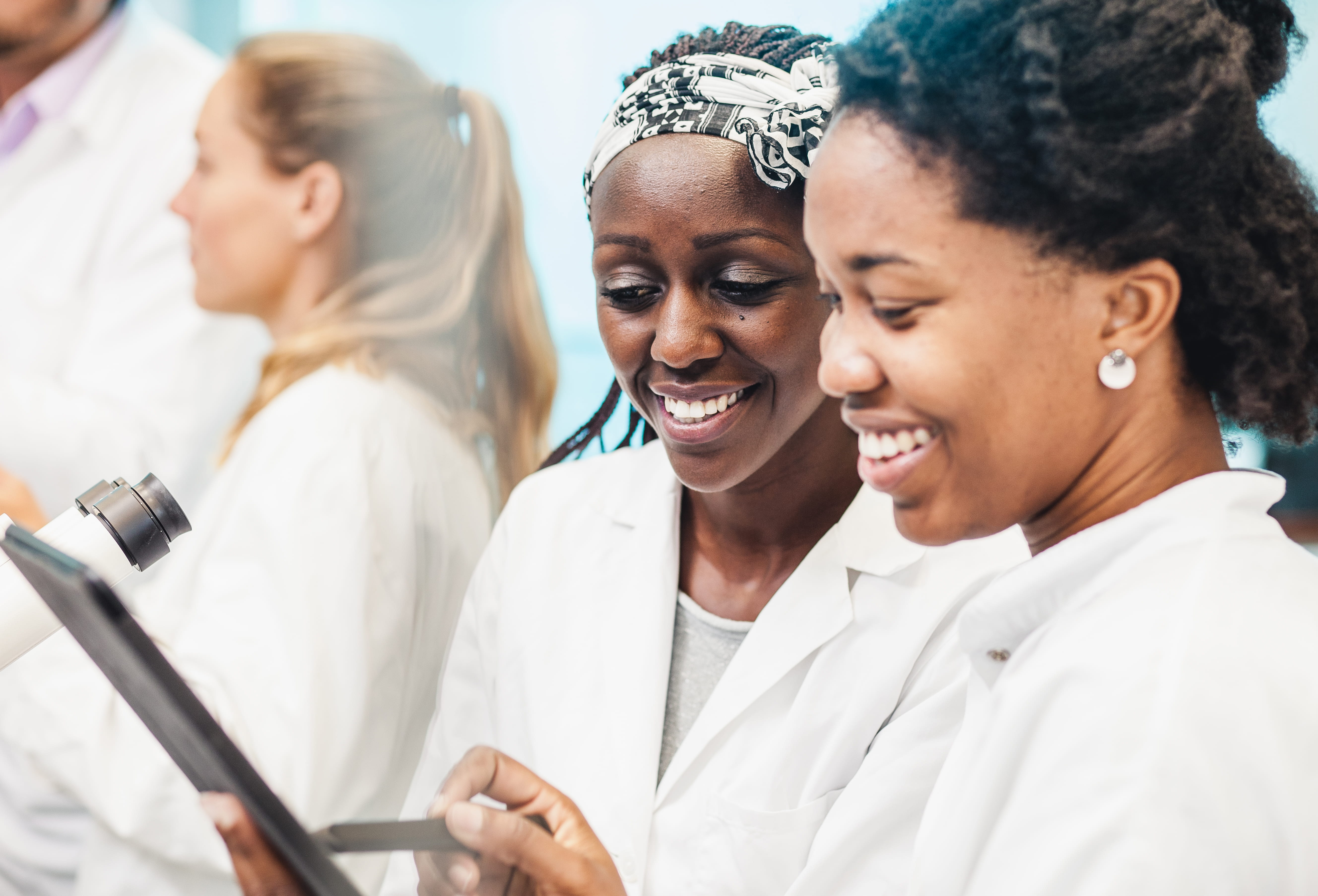 Three female lab workers in white lab coats