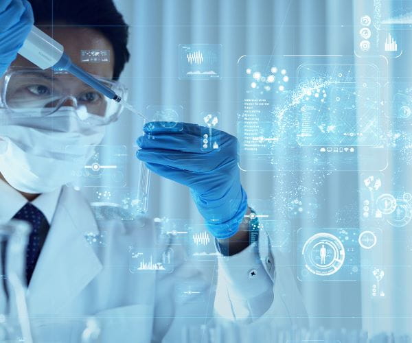 A lab medicine professional pipets a sample in front of a screen displaying data analytics graphics.